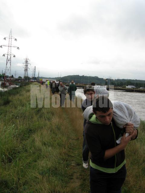 Lanţ de oameni cărând saci cu nisip, pentru a astupa conducta de apă