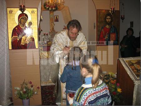 Preotul Constantin Mihoc dând împărtăşanie unor copii, în capela din Berlin, unde slujea de10 ani