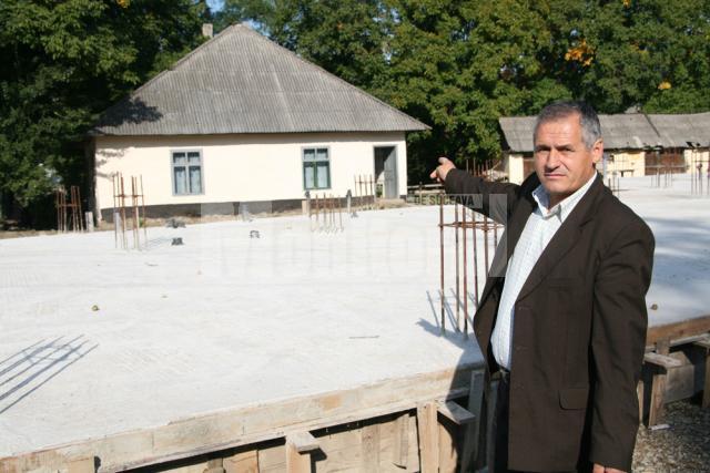 Primarul Toader Gradinariu aratand spre temelia noii scoli din sat care a ramas neterminata din lipsa de fonduri