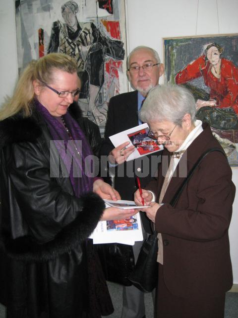 Alma Redlinger oferindu-i un autograf - pe catalogul expoziţiei - artistei plastice Lucia Puşcaşu