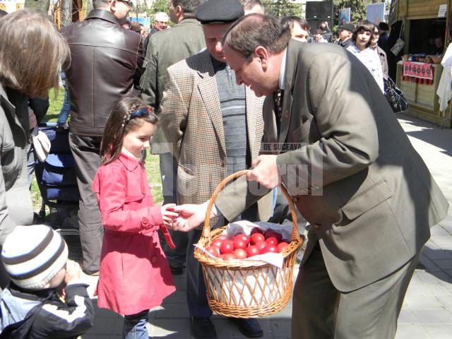 Preşedintele CJ Suceava, Gheorghe Flutur, ajutat de angajaţi ai acestei instituţii au împărţit spectatorilor câte un ou roşu şi o felie de cozonac