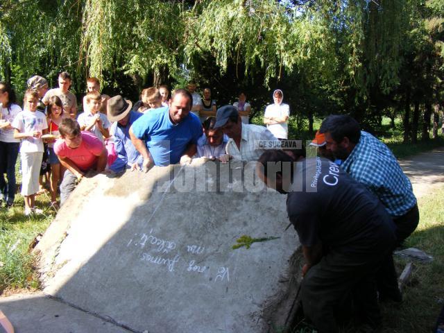 Credincioşi din Fântânele asistând la ridicarea plăcii de beton fisurate şi descoperirea osemintelor umane. Foto: Ionel CURCAN