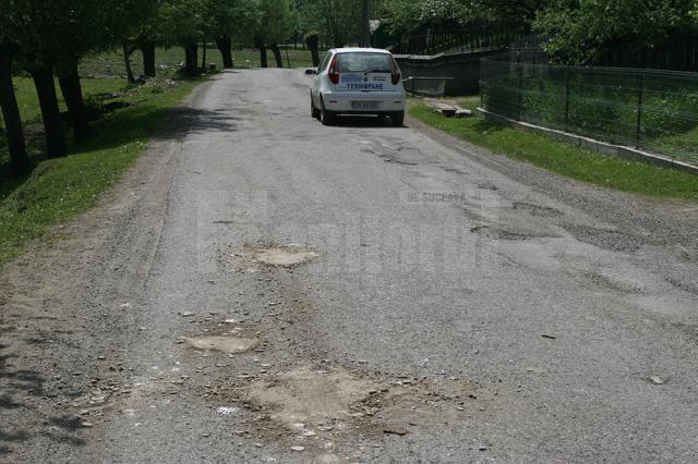 Drum asfaltat cu fonduri europene, reparat în bătaie de joc cu pământ şi piatră