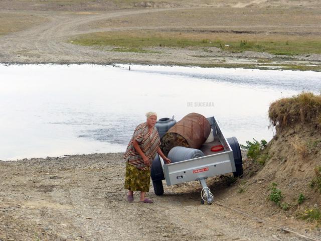 Oamenii care apă cu butoaiele din râul Suceava