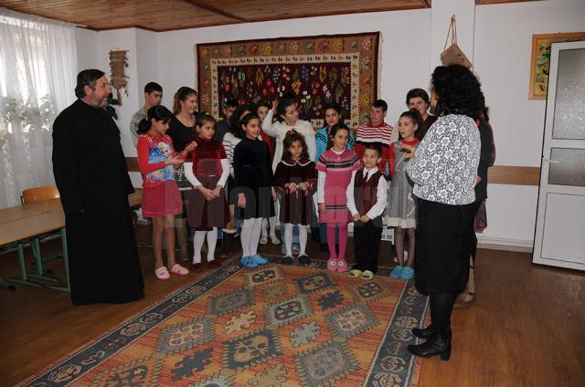 Copiii cântă împreună cu părintele şi preoteasa Mioara cântece pentru Moş Nicolae