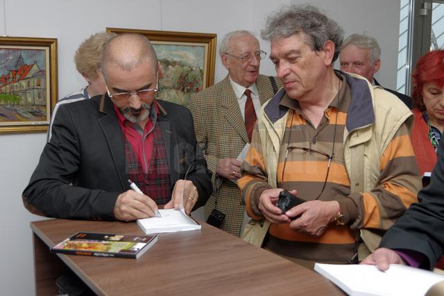 Tiberiu Cosovan dând autografe pe al patrulea volum din cartea „Efigii în filigran”
