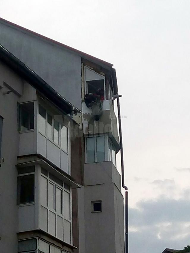 "Batman"-ul Dorel, lucrând la izolarea termică a unui balcon aflat la etajul cinci al clădirii, ţinut de haină de un coleg