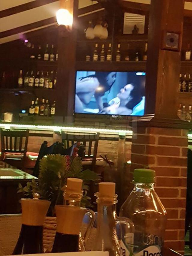 Pe ecranul televizorului situat deasupra barului au rulat scene porno, dintr-un film pentru adulţi