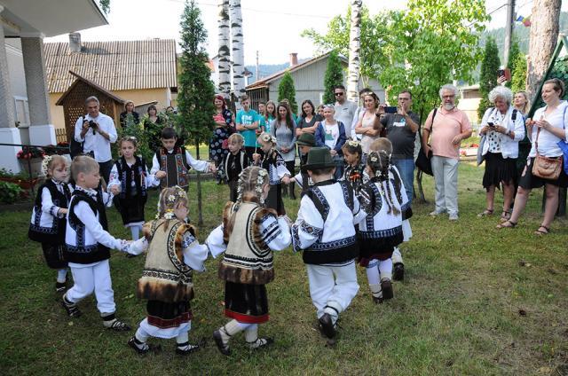 Oaspeţii, întâmpinaţi la liceul din Moldovița de un grup de copii dansând tradiţional