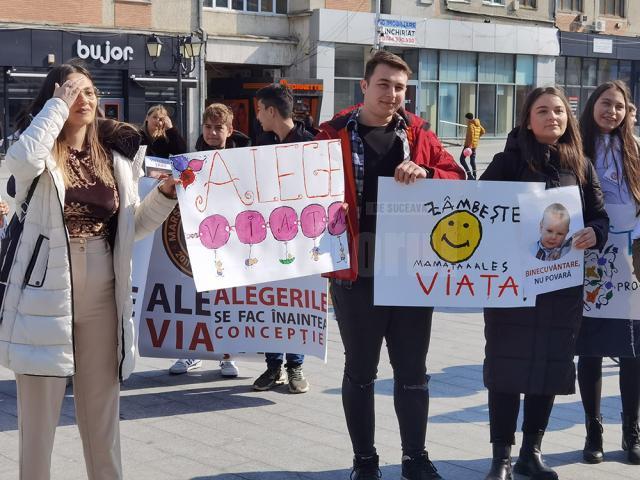 Zeci de tineri cu pancarte și bannere cu mesaje antiavort, de susținere a miracolului vieții, la evenimentul organizat de Buna Vestire, în centrul Sucevei
