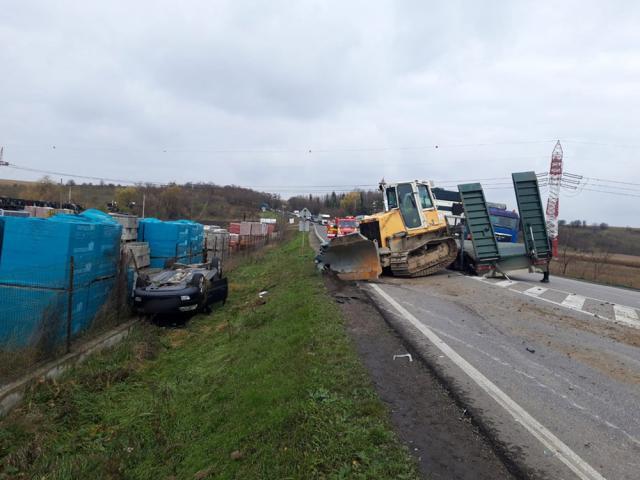 Utilaj căzut de pe o platformă, peste două autoturisme, în trafic