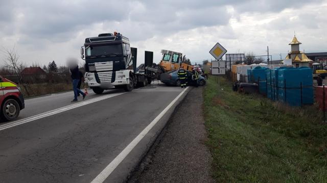 Utilaj căzut de pe o platformă, peste două autoturisme, în trafic