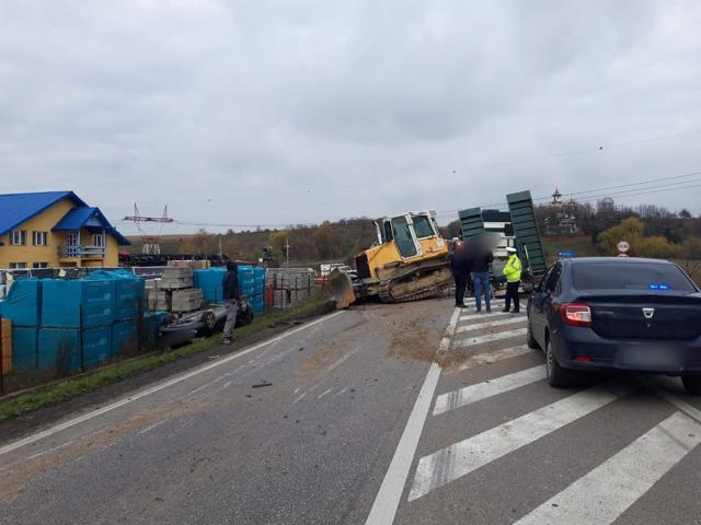 Utilaj căzut de pe o platformă, peste două autoturisme, în trafic