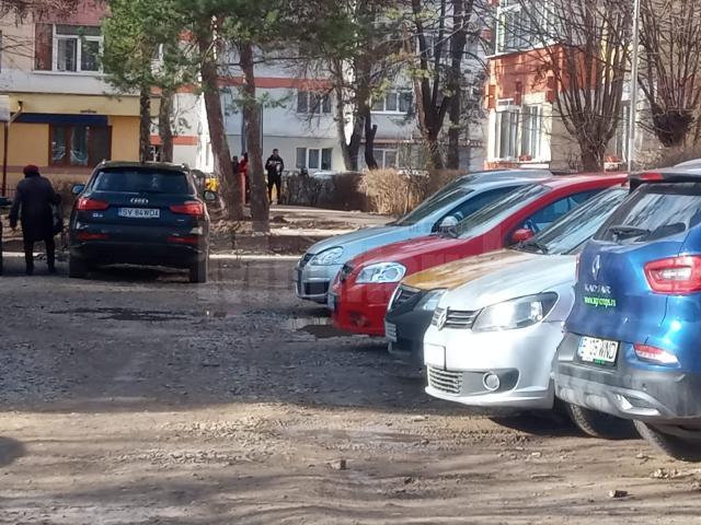 Un teren mocirlit, ocupat de mașini, „spațiul verde” din zona Pieței George Enescu, pentru care s-a luat decizia care permite amenajarea sa ca parcare de reședință