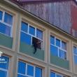 Elev cocoțat pe geam, la exteriorul clădirii