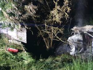 O mașină care a lovit un cap de pod s-a răsturnat și a luat foc